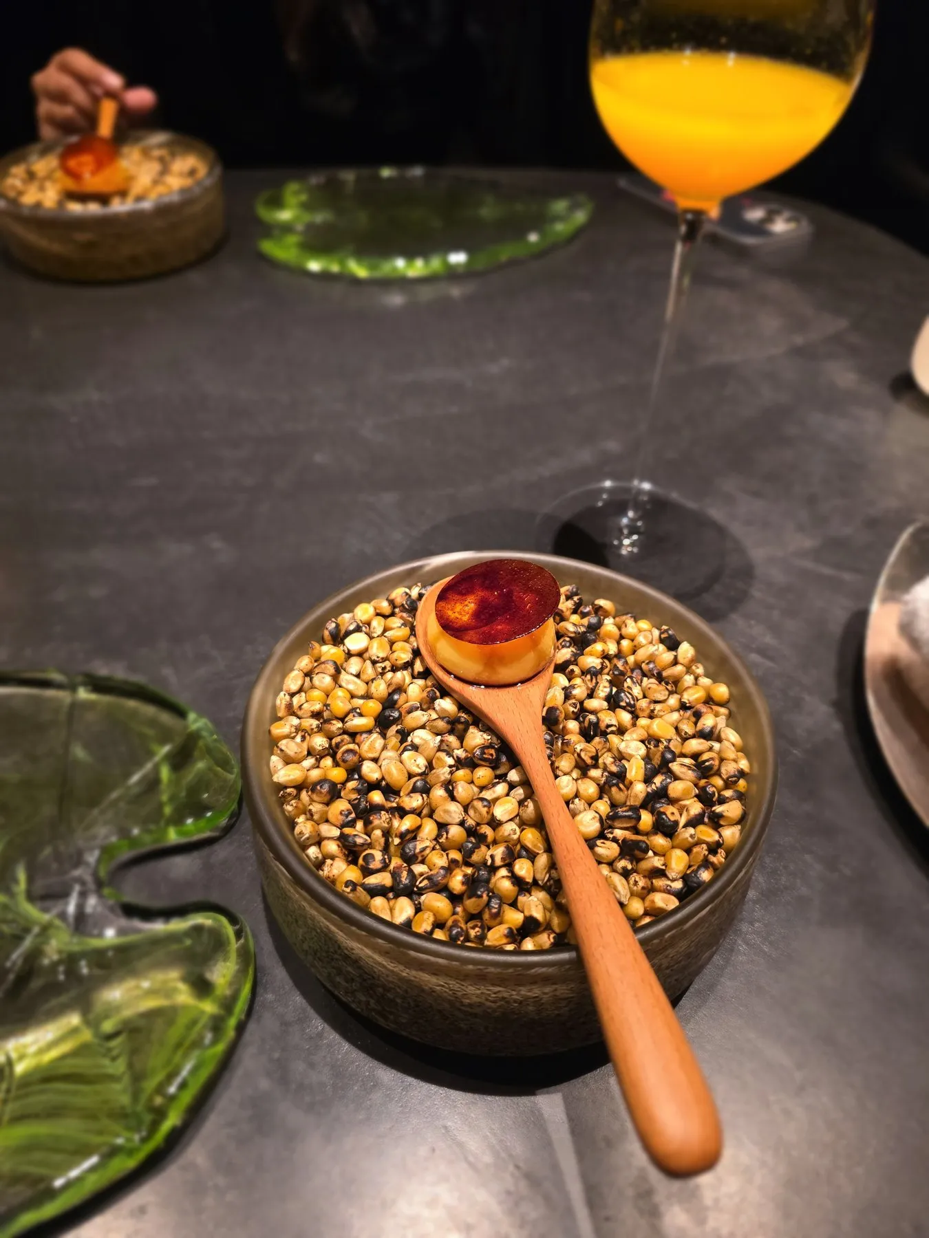 Flan on a wooden spoon over dried corn kernels