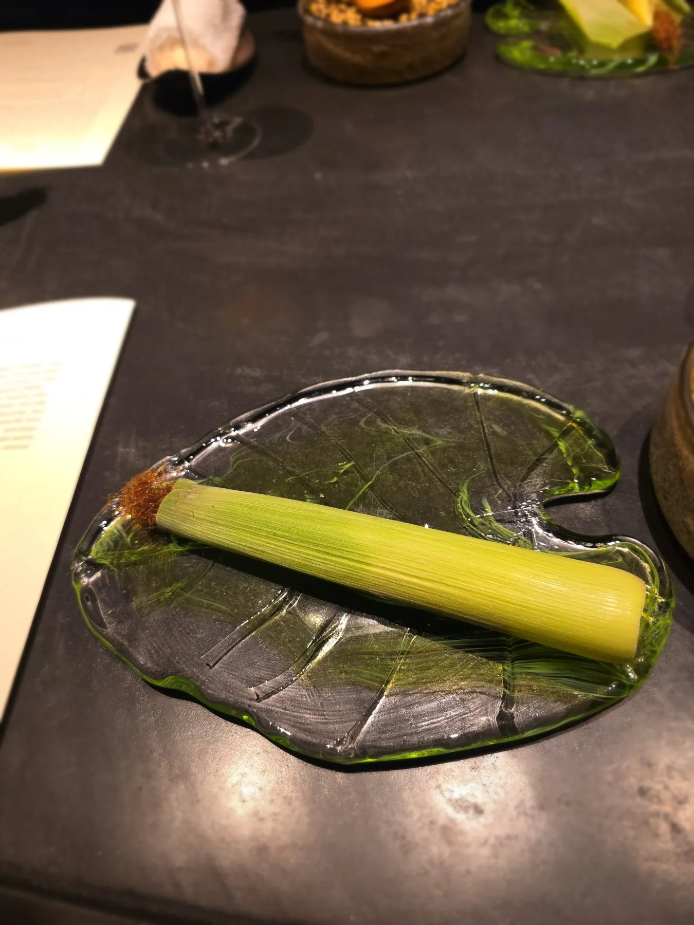 Ear of corn in its husk on a glass leaf plate