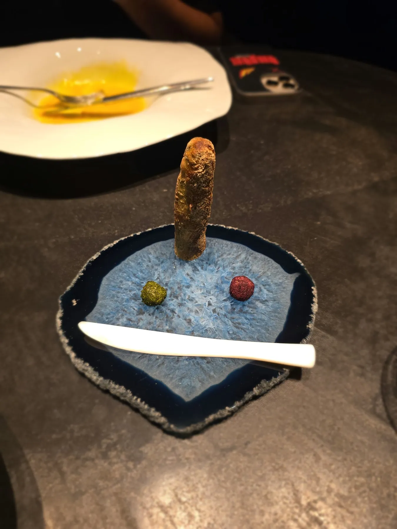 Breadstick and two butter spheres on a blue agate slice