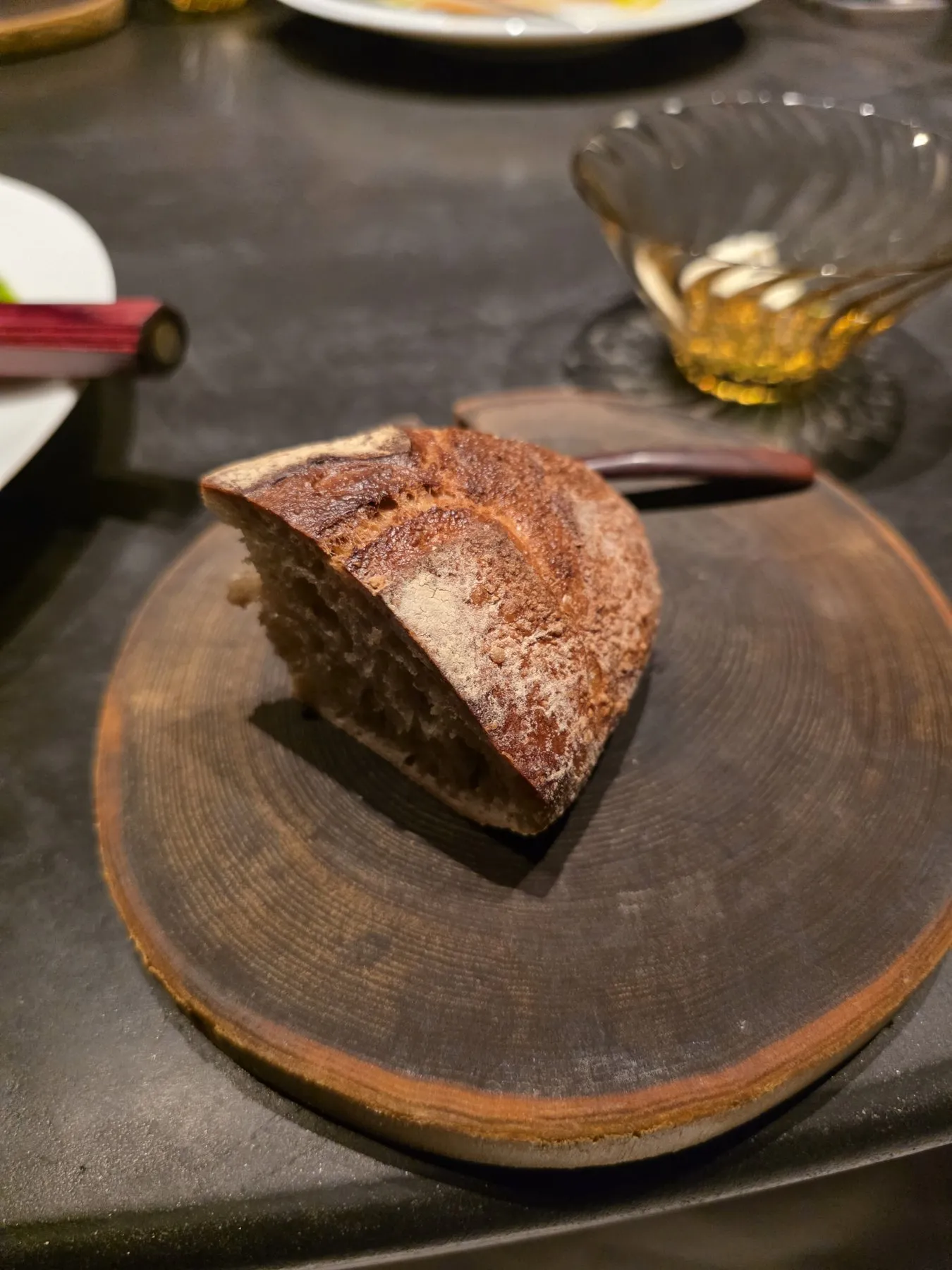 Wedge of dark crusted bread on a wooden board