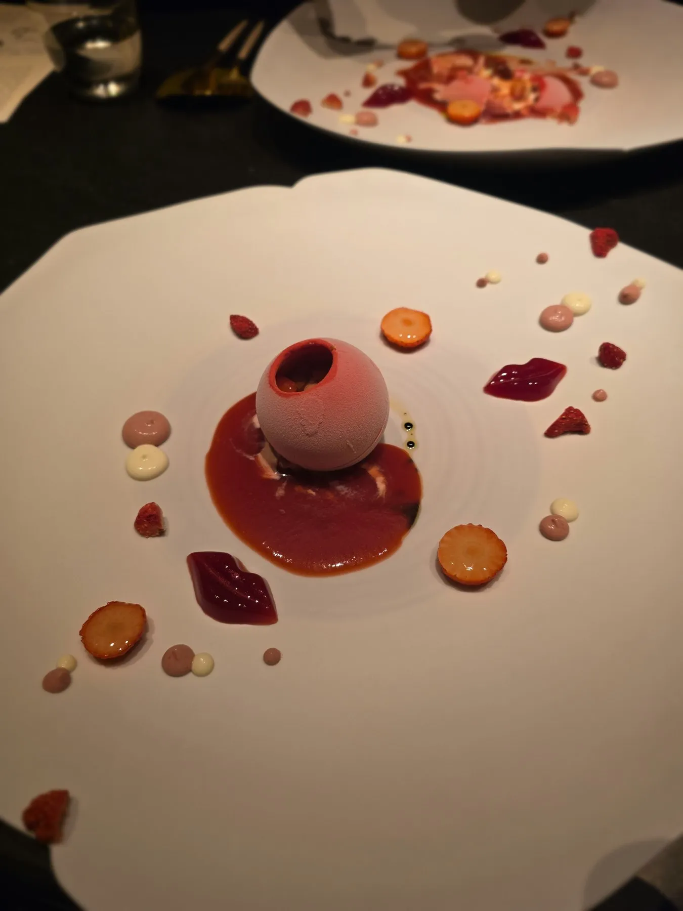 Pink sphere on a white plate with dots of sauce