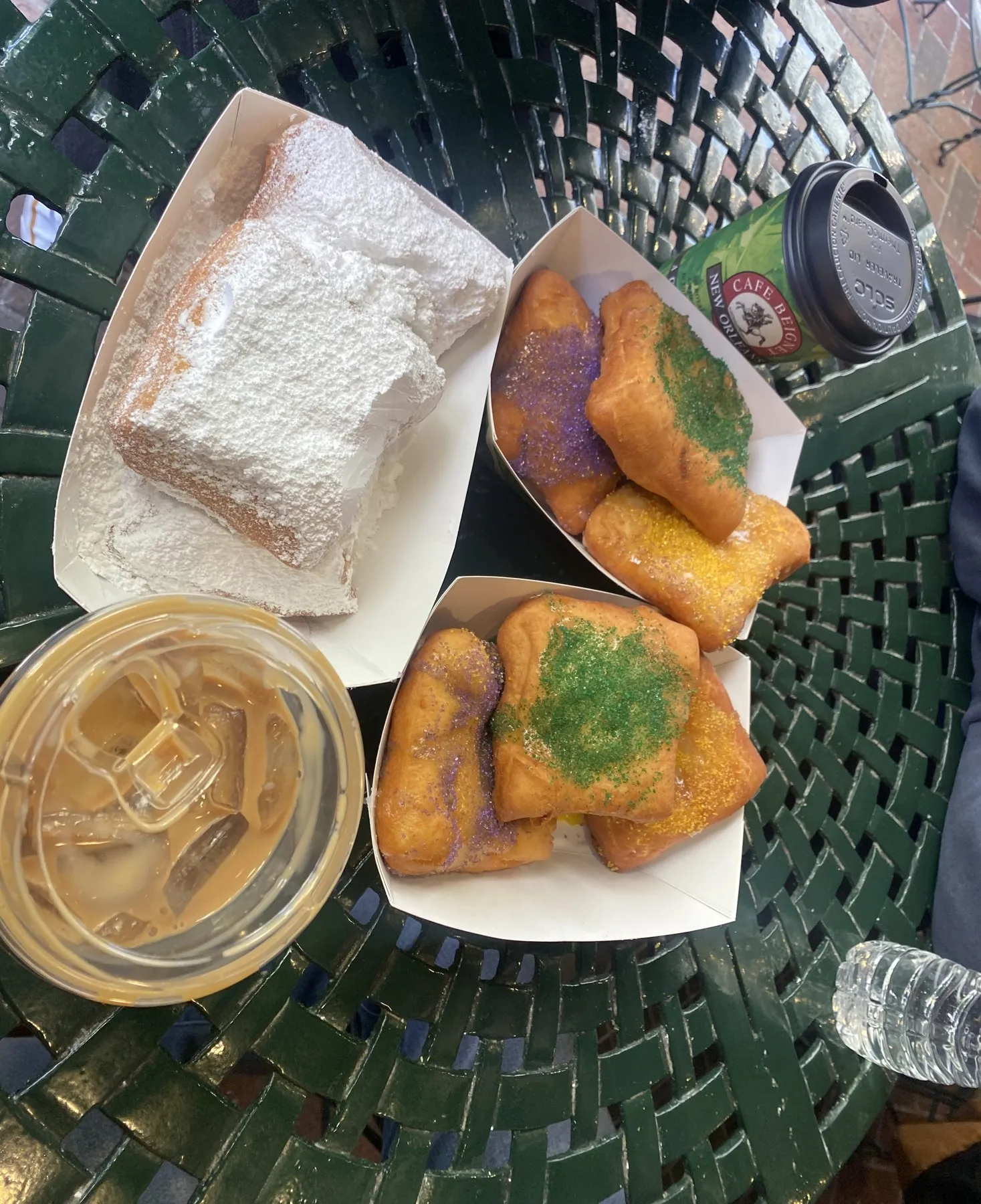 Beignets with colored sugar on a green table