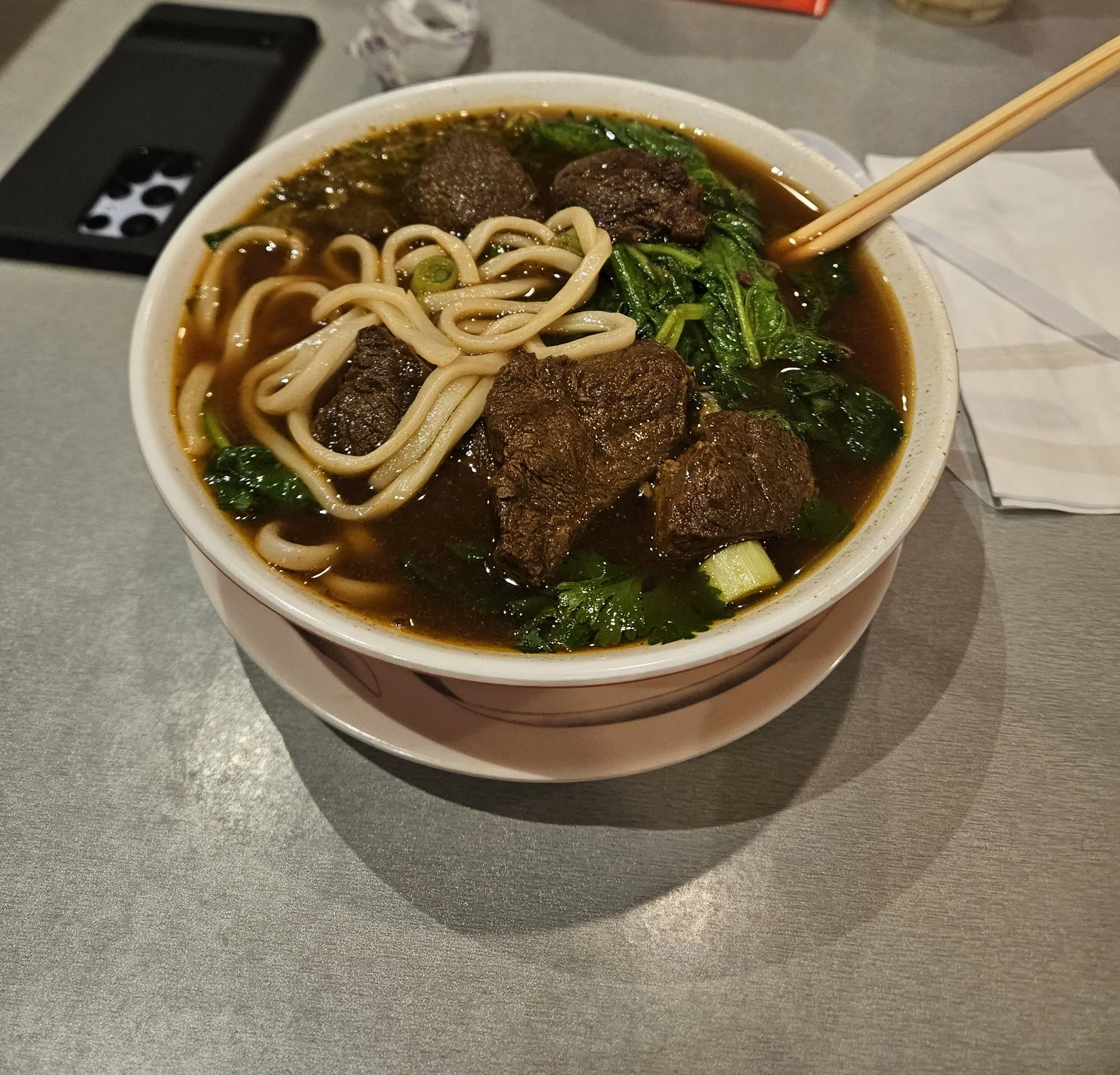 Bowl of beef noodle soup with greens