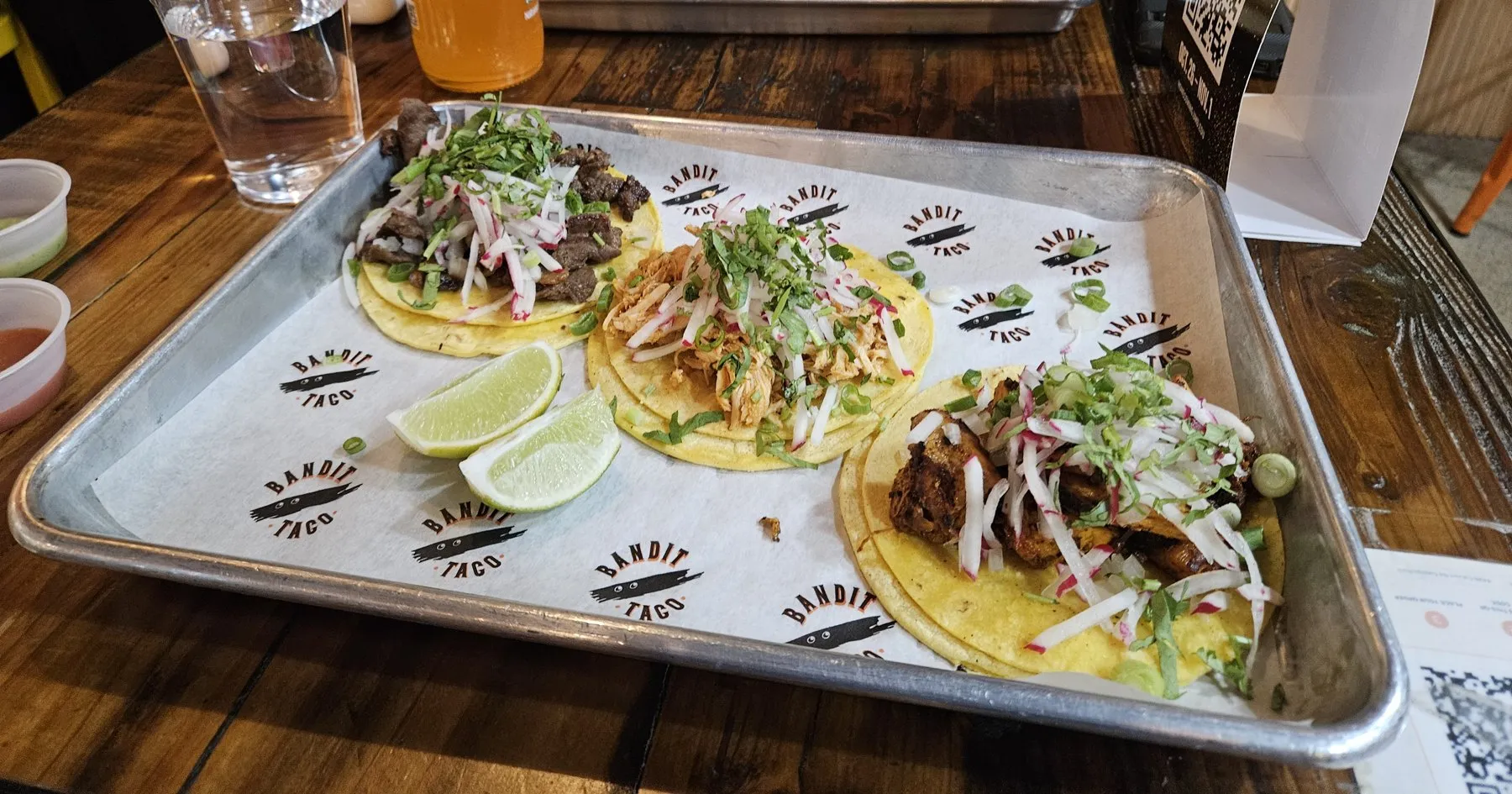 Three tacos on a metal tray