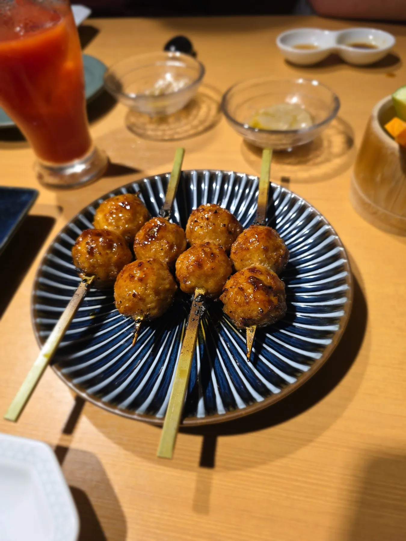 Tsukune skewers on a striped plate