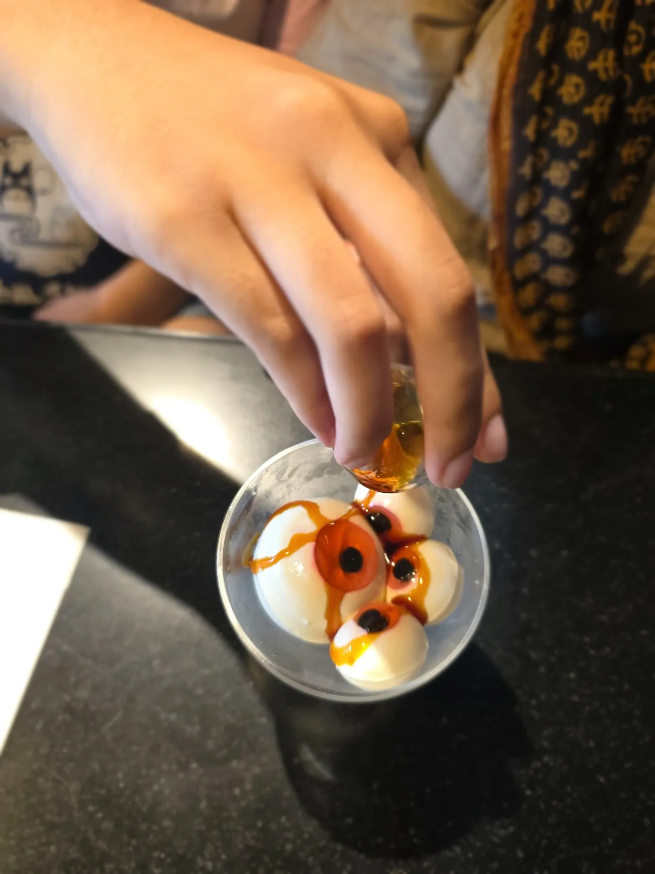 Hand dropping a topping into a glass of shiratama dumplings