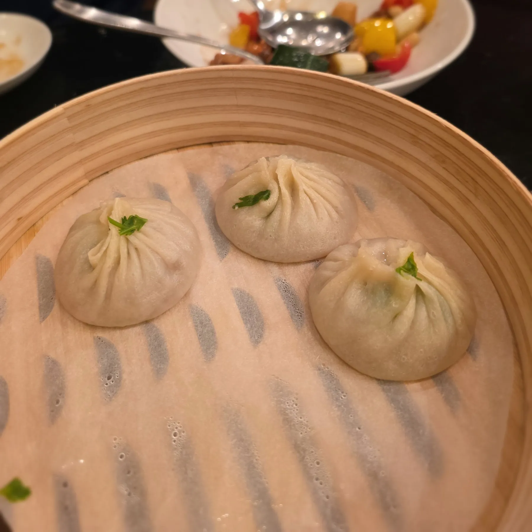 Three xiao long bao in a bamboo steamer