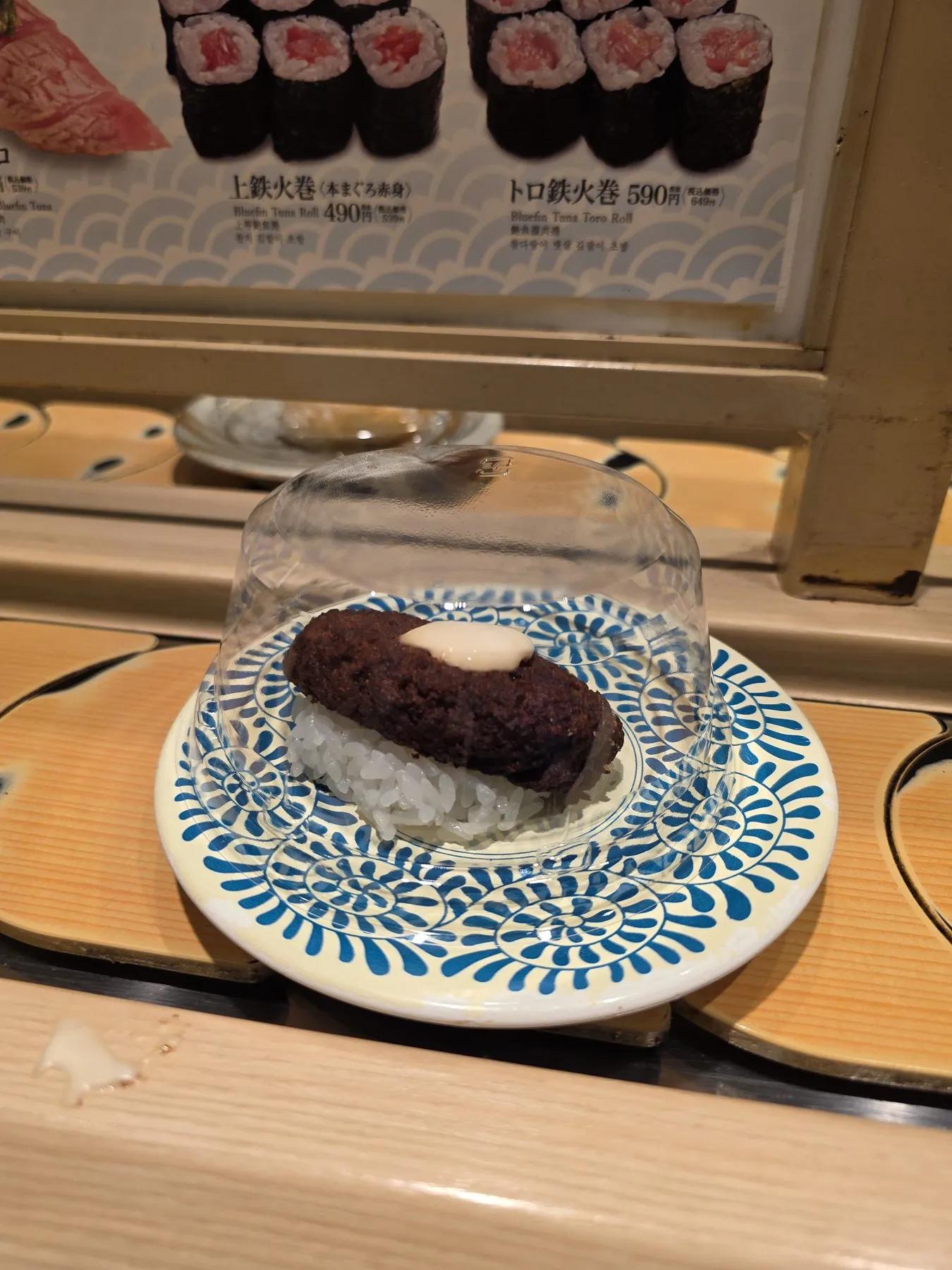 Sushi plate under a cover on a conveyor belt